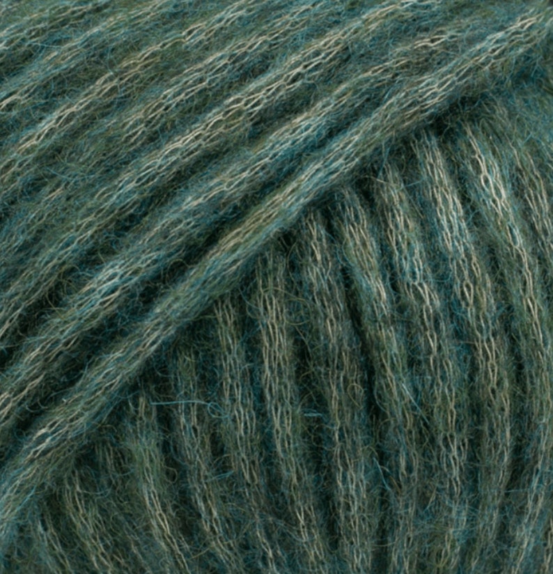 May include: Close-up of a skein of teal and green yarn. The yarn is soft and fluffy, with a subtle sheen.