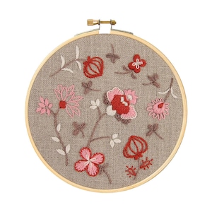Puede incluir: Proyecto de bordado terminado con un diseño floral en un aro de madera. El diseño incluye flores y hojas rosas, rojas y blancas sobre un fondo de tela beige. El aro de madera está asegurado con un tornillo de latón.
