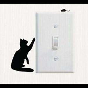 Puede incluir: Una silueta negra de un gato que alcanza un interruptor de luz con una pequeña silueta de ratón en la parte superior del interruptor.