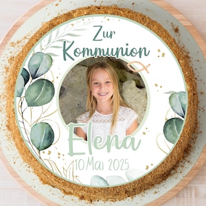 Könnte beinhalten: Ein weißer Tortendecker mit grünem und goldenem Blumendesign. Der Topper zeigt ein Foto eines Mädchens, den Text "Zur Kommunion", den Namen des Mädchens "Elena" und das Datum "10.Mai 2025".