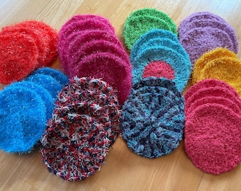 May include: A collection of colorful crocheted scrubbers in various colors, including red, blue, green, purple, and yellow. The scrubbers are made of soft, fluffy yarn and are perfect for cleaning dishes or other surfaces.