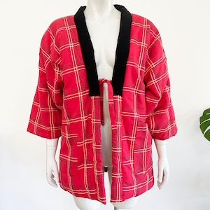 May include: A red and white plaid kimono with black velvet trim. The kimono is tied at the waist and has a relaxed fit.