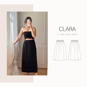 May include: A woman wearing a black crop top and a black midi skirt. The top has a ruffled edge and spaghetti straps. The skirt is a-line and reaches mid-calf. The text "CLARA A LINE MIDI SKIRT" is displayed on the right side of the image.