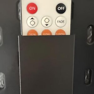 Może przedstawiać: Czarny pilot z białymi przyciskami. Przyciski są oznaczone jako "ON", "OFF", "FADE", "25%", "50%" i "100%".