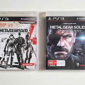 Könnte beinhalten: Zwei PlayStation 3 Videospielhüllen. Die linke Hülle ist für "Metal Gear Solid 4: Guns of the Patriots" mit einer Schwarz-Weiß-Illustration von Soldaten. Die rechte Hülle ist für "Metal Gear Solid V: Ground Zeroes" mit einer Nahaufnahme eines Mannes.