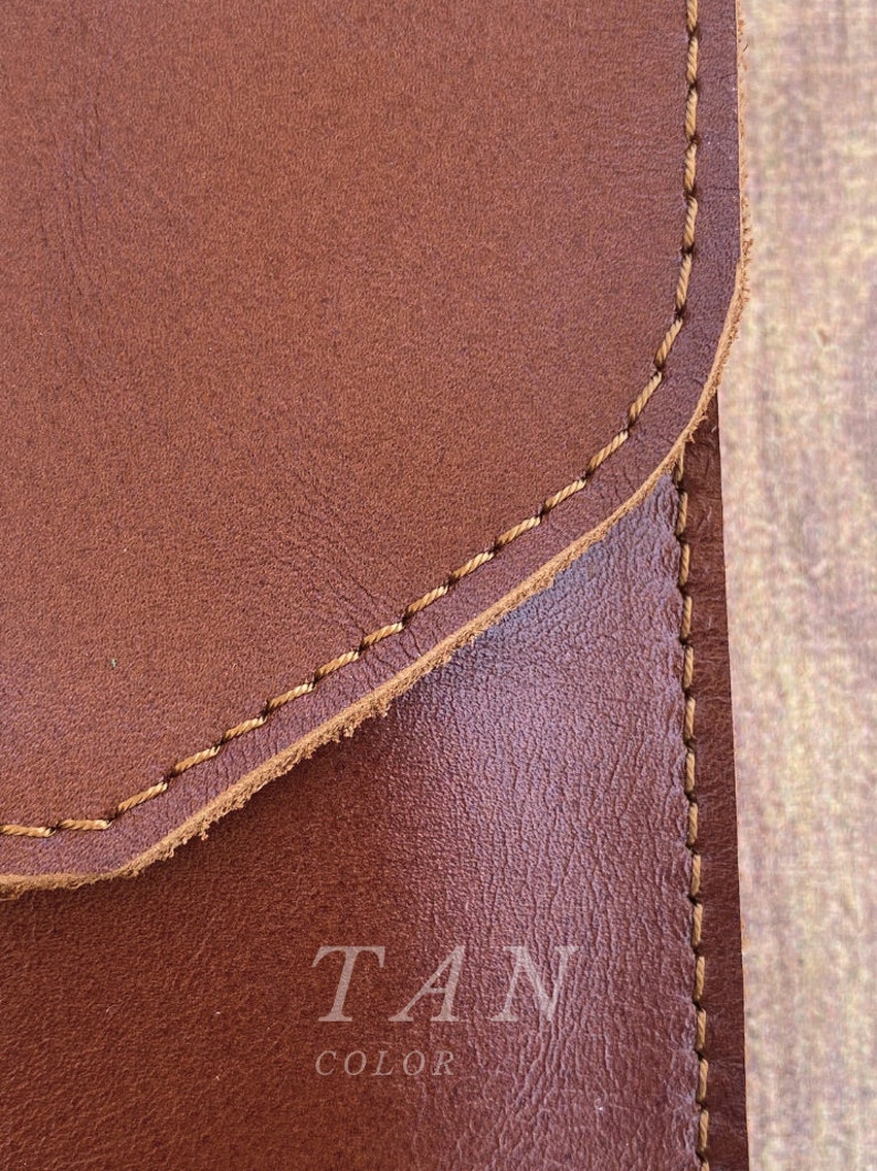 May include: Close-up of a brown leather surface with tan stitching. The text "TAN COLOR" is printed in white on the leather.