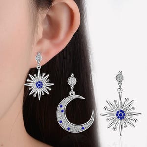 May include: A pair of silver dangle earrings with a blue crystal star and a crescent moon design.