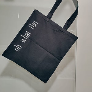 May include: A black tote bag with white text that reads "oh what fun".