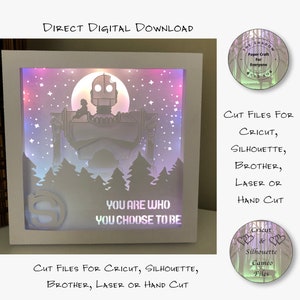 May include: A white light-up shadow box featuring a silhouette of the Iron Giant and a quote that reads "You are who you choose to be". The box is illuminated with colourful LED lights. The image includes the text "Cut Files for Cricut, Silhouette, Brother, Laser or Hand Cut".