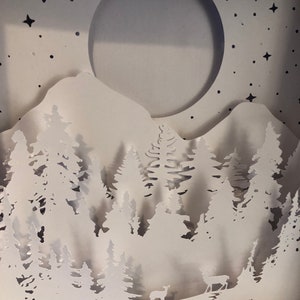 Deer in the Forest Shadow Box SVG design template of a couple walking in the forest with the mountains in the background, can be cut with Cricut, Silhouette Cameo, Brother machines or by hand, designed by The Shadow Box Club
