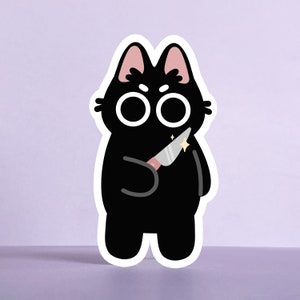 Può includere: Un adesivo di gatto nero con occhi grandi che tiene un coltello d'argento lucido con un manico rosa.