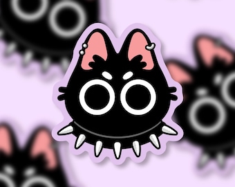 May include: A black cat sticker with large white eyes, pink ears, and a spiked collar. The cat has piercings in its ears and is set against a light purple background. Other blurred cat stickers are in the background.