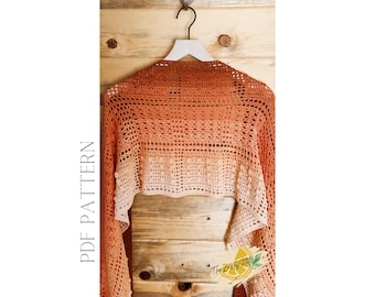 May include: A crocheted shawl in shades of orange and peach, hanging on a wooden hanger. The shawl has a lacy pattern and a scalloped edge. The text "PDF PATTERN" is written vertically on the left side of the image.