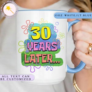 May include: A white ceramic mug with a black handle and the text "But First, Coffee" in a black, handwritten-style font. The mug is on a white surface.