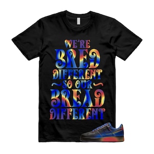 Puede incluir: Camiseta negra con el texto "WE'RE BRED DIFFERENT SO OUR BREAD DIFFERENT" en un diseño degradado colorido. Un par de zapatillas negras y azules con suela roja están en la parte inferior derecha.