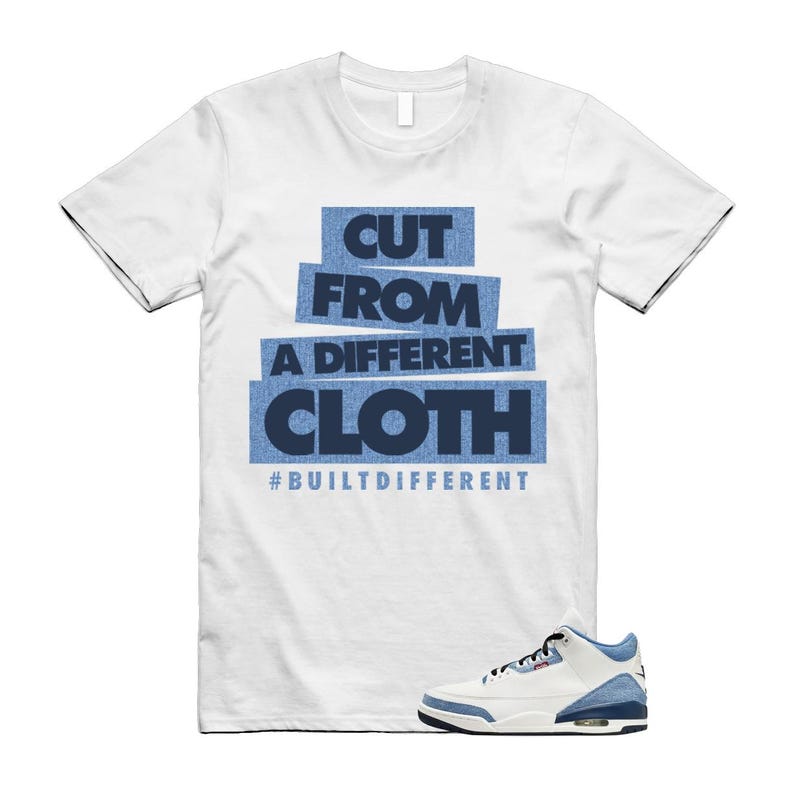 Puede incluir: Camiseta blanca con el texto "CUT FROM A DIFFERENT CLOTH" en letras azules y el hashtag "#BUILTDIFFERENT". Una zapatilla deportiva blanca y azul se muestra en la parte inferior derecha.