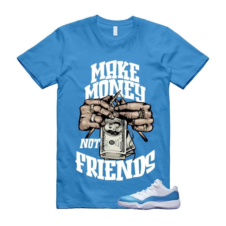Puede incluir: Una camiseta azul claro con el texto "MAKE MONEY NOT FRIENDS" en blanco. El gr&aacute;fico muestra manos sosteniendo agujas de tejer con un billete de d&oacute;lar. Un par de zapatillas blancas y azul claro en la parte inferior.