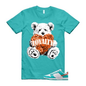 May include: Turquoise t-shirt with a white teddy bear holding orange roses and the word "LOYALTY". White and turquoise trainers with orange accents are at the bottom of the image.