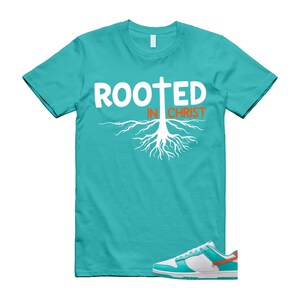 May include: A turquoise t-shirt with the words "ROOTED IN CHRIST" in white and orange, featuring a cross and root design. A pair of white, turquoise, and orange trainers are at the bottom of the image.