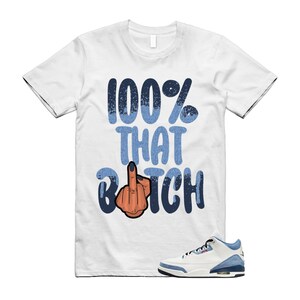 May include: White t-shirt with the text "100% THAT BITCH" in blue and a graphic of a hand with the middle finger raised. A pair of white and blue sneakers is at the bottom right.