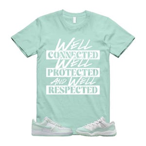 Puede incluir: Una camiseta verde claro con las palabras blancas "WELL CONNECTED, WELL PROTECTED, AND WELL RESPECTED". La imagen también muestra zapatillas deportivas a juego en verde claro y blanco.