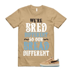 May include: Tan t-shirt with the text "We're Bred Different So Our Bread Different" in white and light blue. A tan and blue sneaker is in the lower right corner.