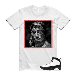 May include: A white short-sleeve t-shirt featuring a black and white portrait of Tupac Shakur wearing a bandana, enclosed in a red Greek key border. Below the shirt is a high-top sneaker with a white upper, black mudguard, and black laces.