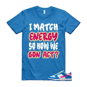 May include: A blue t-shirt with the text "I MATCH ENERGY SO HOW WE GON ACT?" in white and pink lettering. A pair of blue, white, and pink sneakers are in the lower right corner.