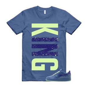 May include: Blue t-shirt with the word "KING" in lime green and navy blue. A blue sneaker with a green sole is next to the shirt.