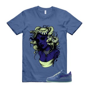 May include: Blue t-shirt featuring a graphic of Medusa with snakes, in shades of purple, yellow, and white. A pair of blue sneakers with a purple swoosh are next to the shirt. The sneakers have a translucent sole.