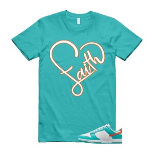 May include: A turquoise t-shirt with an orange and white heart design, with the word "Faith" in a cursive font. White, turquoise, and orange trainers are in the foreground.