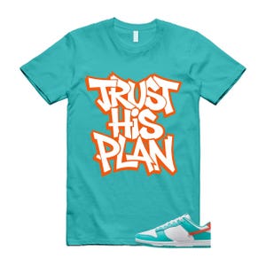 May include: Turquoise t-shirt with the words "TRUST HIS PLAN" in white with orange outlines. A pair of white, turquoise, and orange trainers are at the bottom. The shirt is a crew neck style.