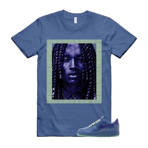 May include: A blue t-shirt featuring a portrait of a person with long braids, framed by a green Greek key design. A pair of blue sneakers with a purple swoosh and green sole are in the foreground. The shirt and shoes are on a white background.