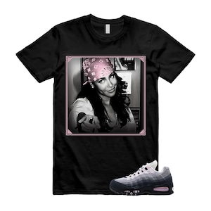 May include: Black t-shirt featuring a black and white image of a person wearing a pink bandana, with the text "HIMV" in the upper right corner. A pair of gray and black sneakers with pink accents are at the bottom.