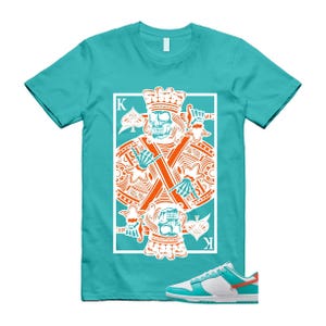 May include: Teal t-shirt with a playing card design featuring a skull king graphic in orange and white. The shirt is paired with teal, white, and orange trainers. The design includes the letter "K" and spade symbols.