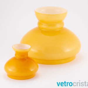 May include: Two yellow glass lampshades, one larger than the other. The larger lampshade is a pale yellow, while the smaller lampshade is a darker, more orange yellow.