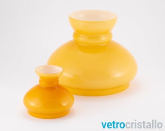May include: Two yellow glass lampshades, one larger than the other. The larger lampshade is a pale yellow, while the smaller lampshade is a darker, more orange yellow.