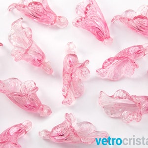 May include: Pink glass flower charms with a delicate, textured design. These charms are perfect for adding a touch of elegance to jewelry or crafts.