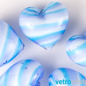 May include: Five blue and white striped glass hearts. The hearts are arranged in a semi-circle on a white background.