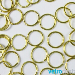 Könnte beinhalten: Nahaufnahme eines Stapels goldener Sprungringe. Die Ringe sind klein und rund und perfekt für die Schmuckherstellung.