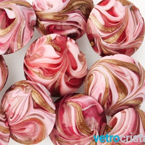 Peut inclure: Un ensemble de perles en verre rose et blanc avec des tourbillons dorés. Les perles sont rondes et ont un aspect marbré.