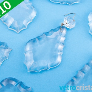 May include: Ten clear crystal teardrop-shaped chandelier prisms with a faceted design. The prisms are on a blue background.