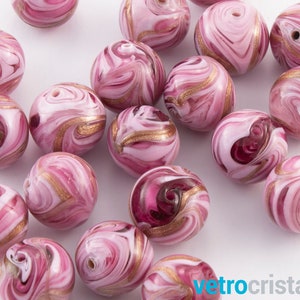 May include: A collection of pink and white glass beads with gold swirls. The beads are round and have a marbled effect.