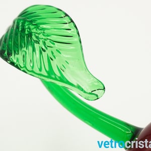 May include: Close-up of a green glass cherry stem with a leaf. The leaf has a detailed, textured design.