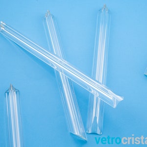 May include: Five clear glass rods with pointed ends, arranged on a light blue background. The rods are approximately 10 inches long and have a slightly curved shape.