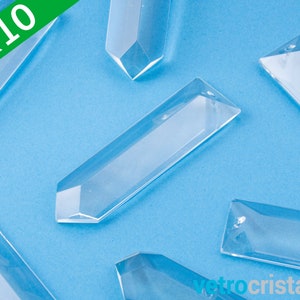 Puede incluir: Diez colgantes de prisma de vidrio transparente, cada uno con un extremo puntiagudo y una forma rectangular plana. Los prismas están dispuestos sobre un fondo azul.