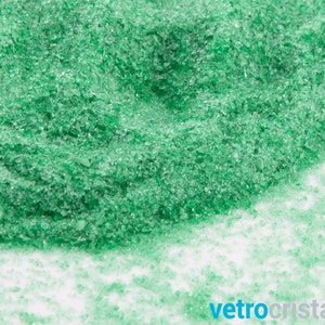 May include: A close-up of a pile of green crushed glass. The glass is small and sparkly, and it looks like it could be used for crafts or decorations.