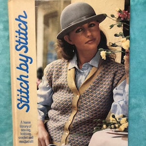 May include: A vintage book cover titled "Stitch by Stitch" with a woman wearing a gray hat and a patterned sweater. The book cover also includes the text "A home library of sewing, knitting, crochet and needlecraft."