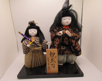 Vintage Japanese dolls on stand with placard