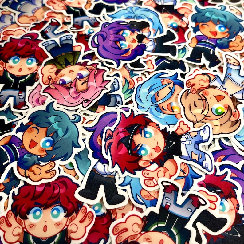 May include: A pile of anime-style stickers. The stickers depict cartoon characters with diverse hair colours, such as red, blue, purple, and blonde. The characters have detailed facial expressions and are in various poses.